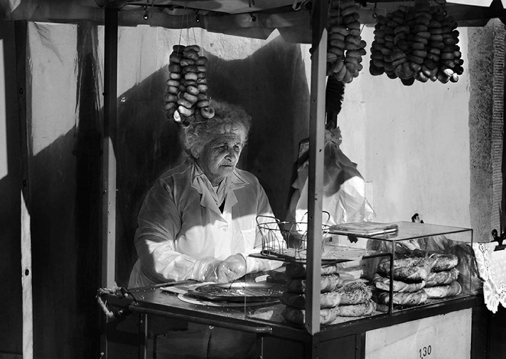 Older woman selling baked goods from a market stall